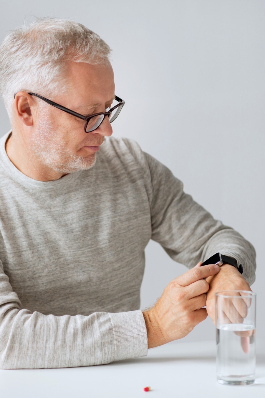 Senior Man with Water and Pill looking at smartwatch