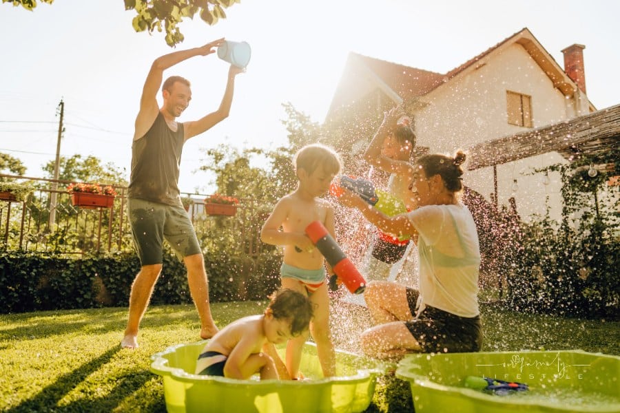 family playing with water guns in the backyard