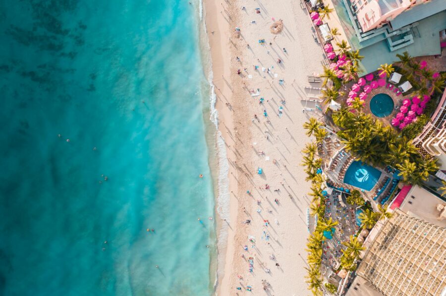 Stunning aerial view of a tropical beach resort in Hawaii with lush palm trees, turquoise water, and golden sands.