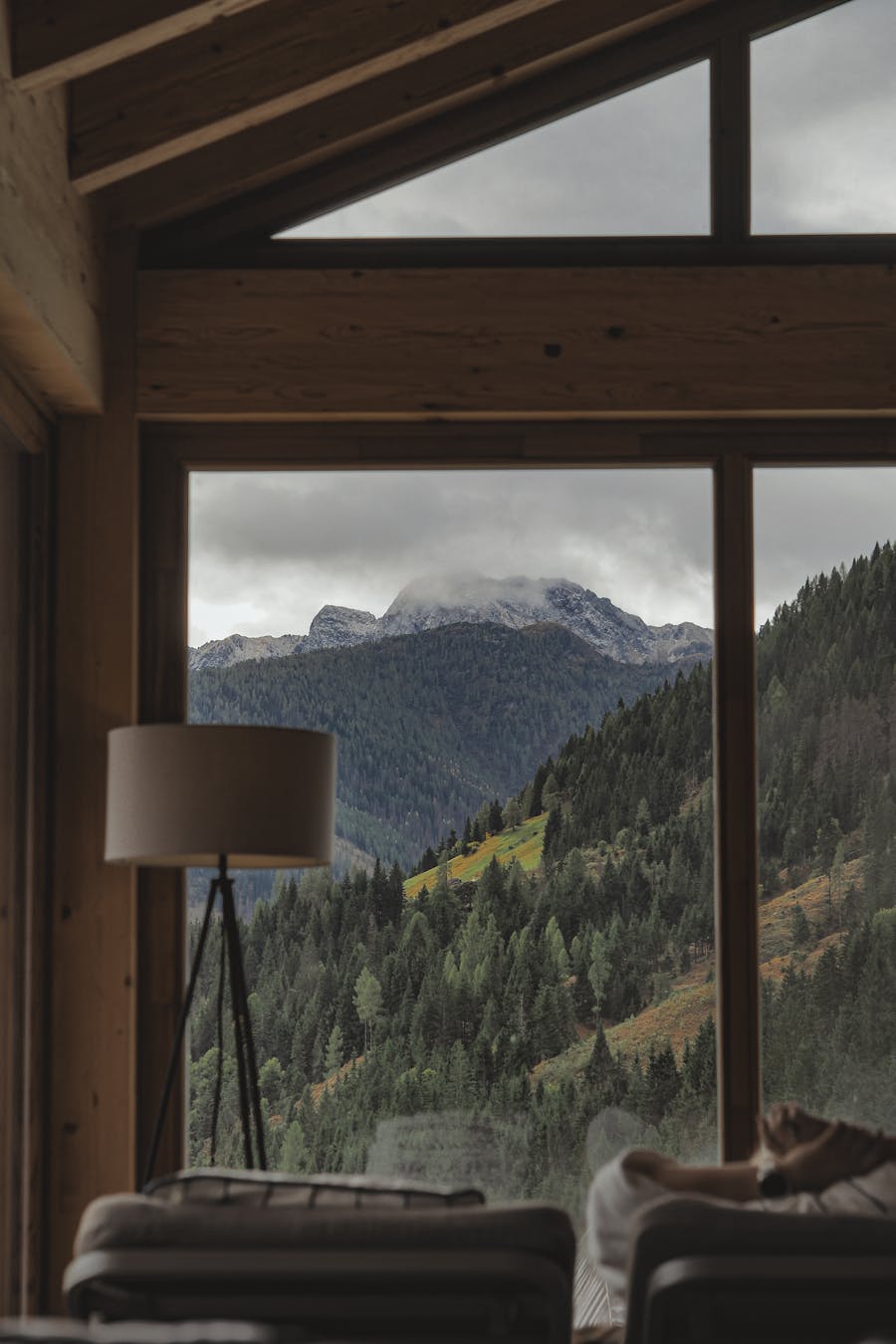 A peaceful cabin bedroom with a large window view of a lush forest enhances relaxation and tranquility.