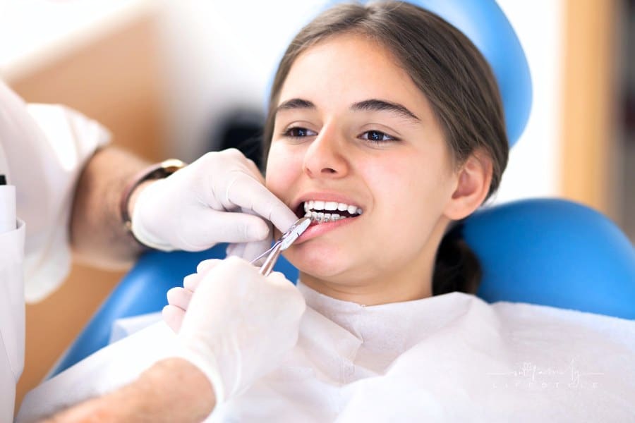 Teenage girl getting braces at orthodontist office