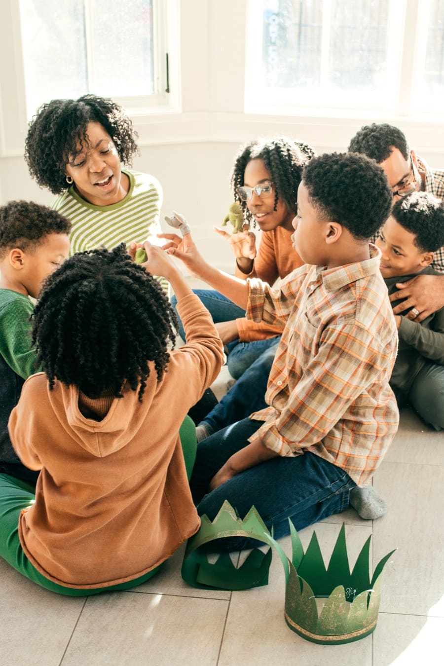 parents with their five children playing with finger puppets and paper crowns on the floor