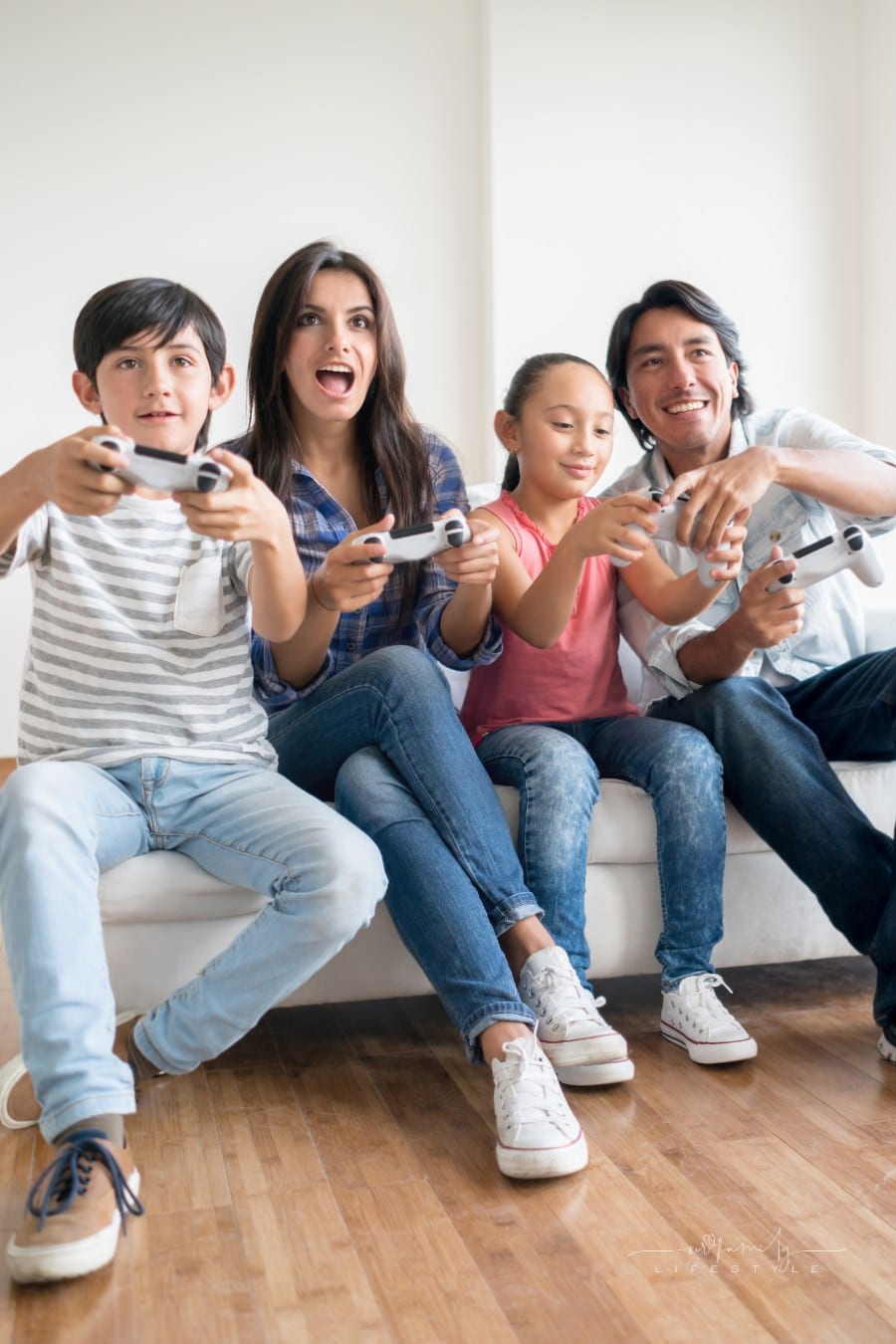 family sitting on couch having fun playing video games together