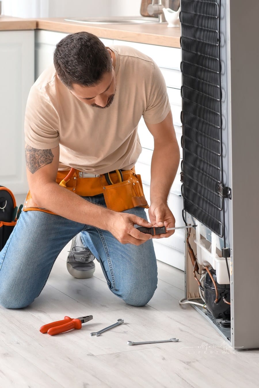 Worker Repairing Fridge in Kitchen