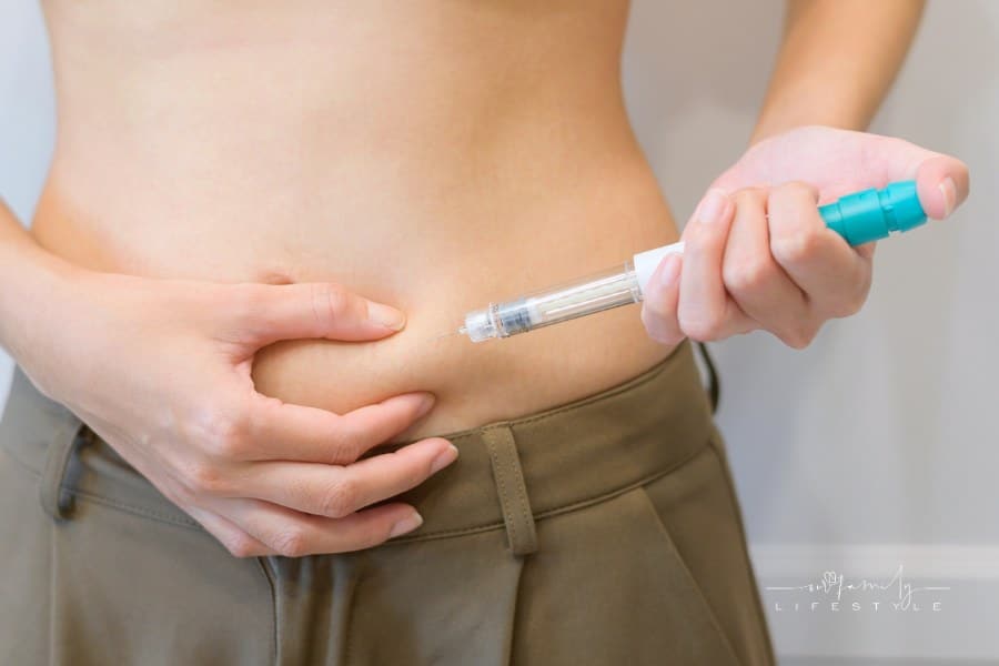 Close up woman using IVF treatment injection on belly