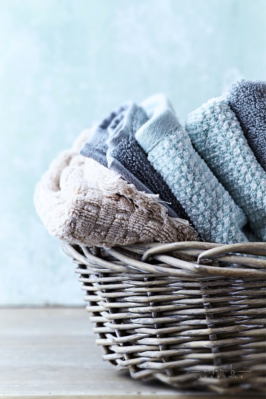 laundry basket with blue and gray towels folded inside