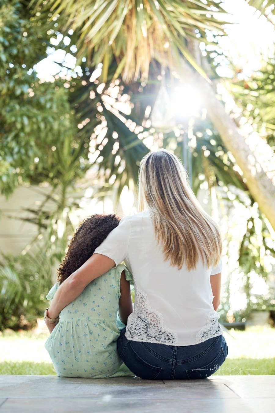 Child, adoption and together with mom for hug, support or love in backyard, garden or family home of girl in foster care. Interracial, mother and daughter bonding in embrace or sitting outdoor.