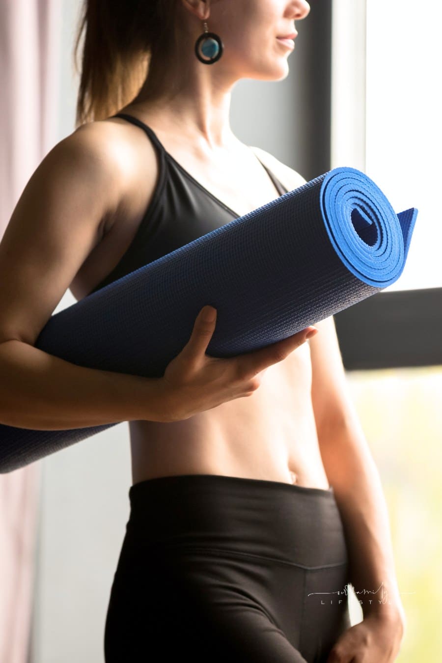 Sporty slim woman holding blue yoga mat