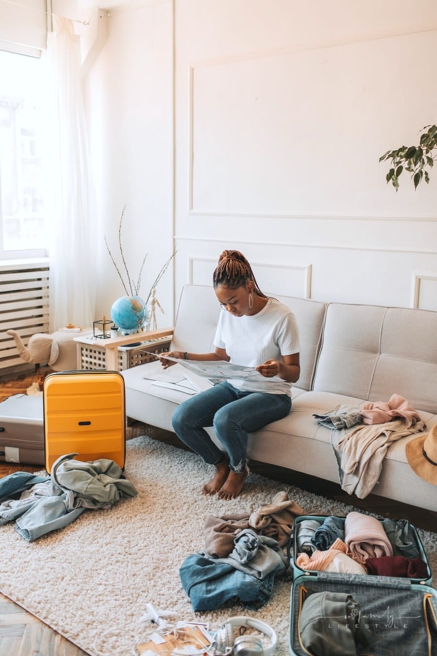 woman looking at map with luggage and clothes around her