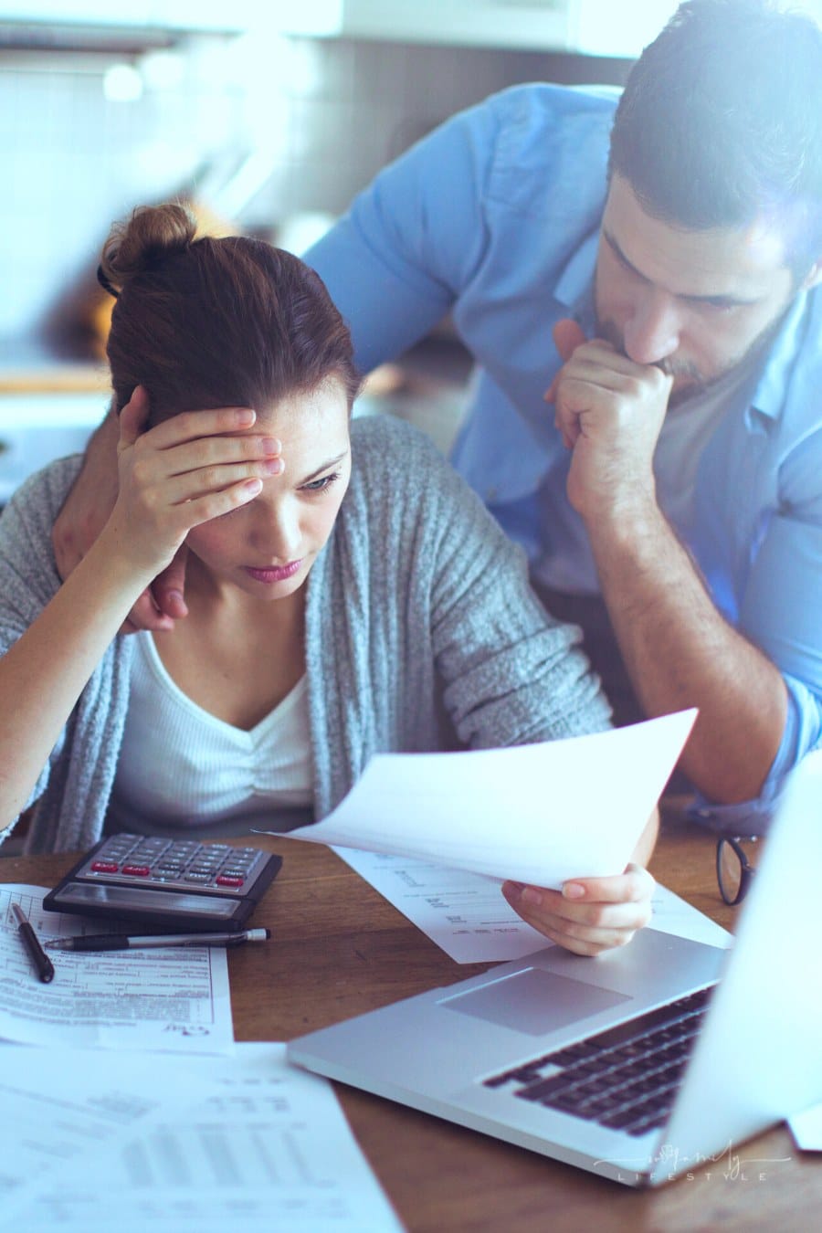 young couple going over expensive bills at kitchen table