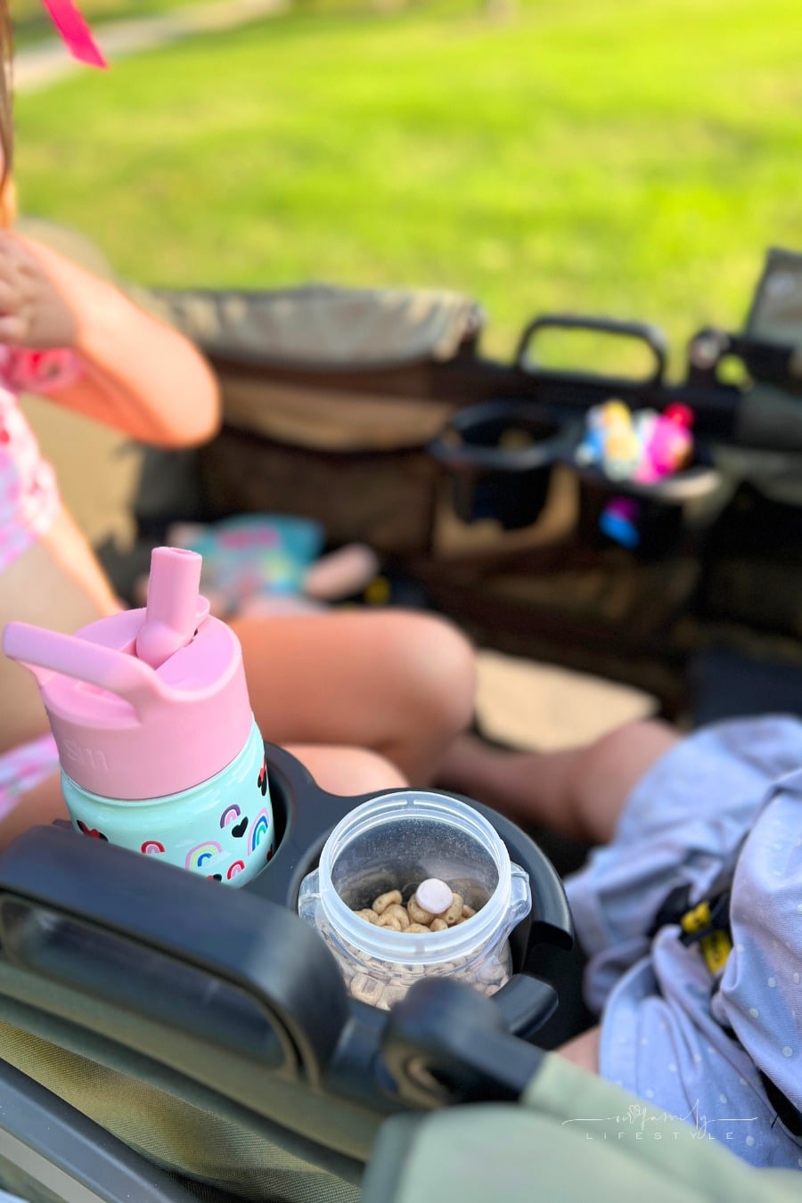 toddlers with snacks and drink in cupholders of stroller wagon