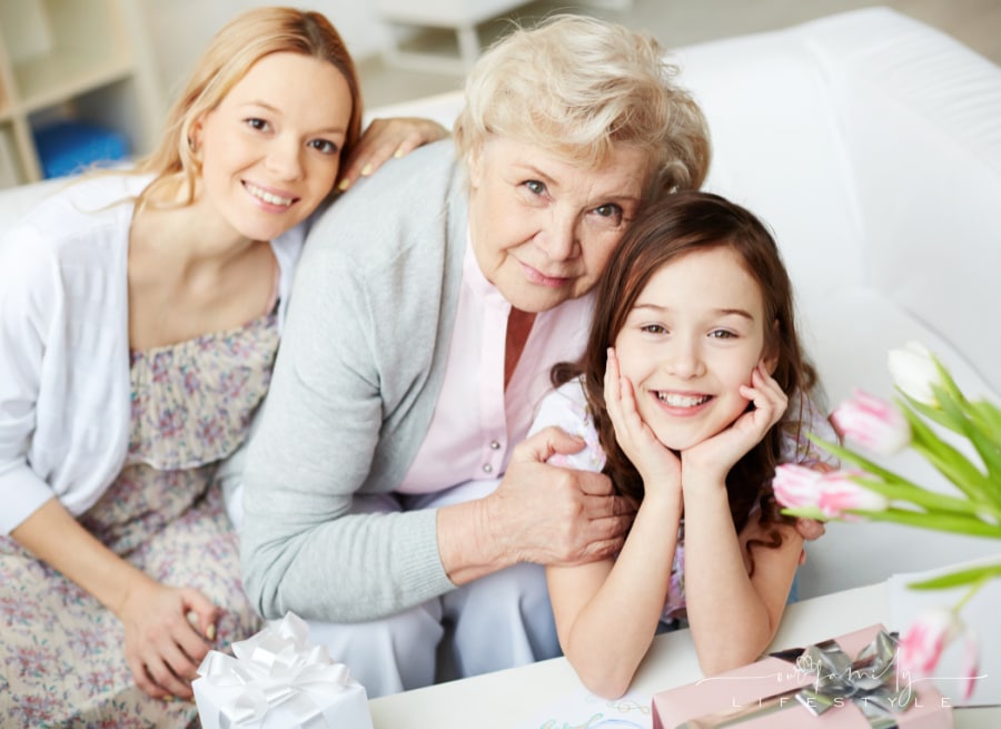 Portrait of happy little girl, her mother and grandmother looking at camera at home