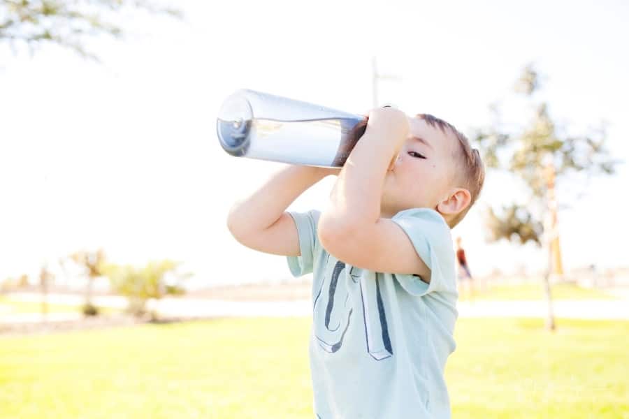 little boy drinking from a reusable water bottle
