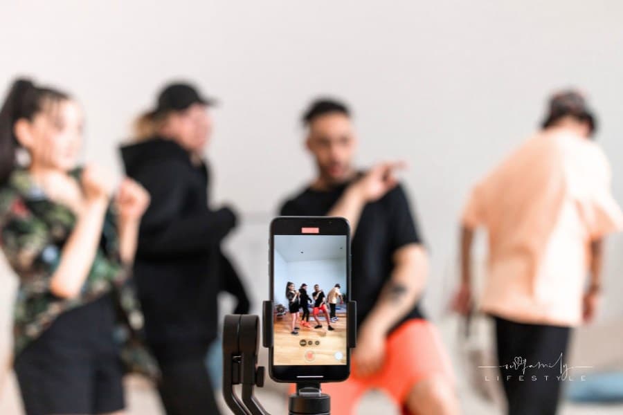 Selective Focus Photography of iPhone on tripod while group of people film TikTok dance