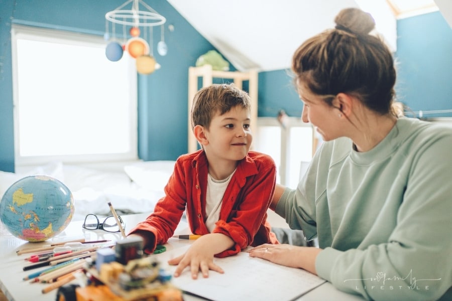 mom patting young son on back while homeschooling