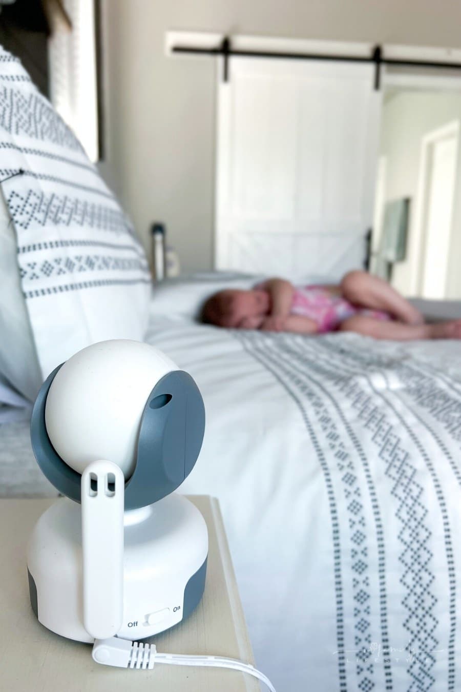toddler sleeping in bed with baby monitor camera pointed at her