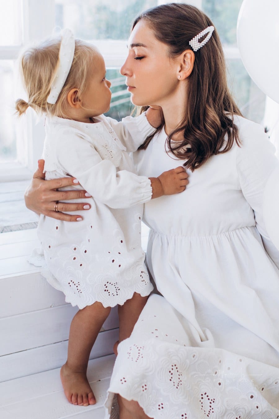 mom is holding toddler daughter while both are looking at each other