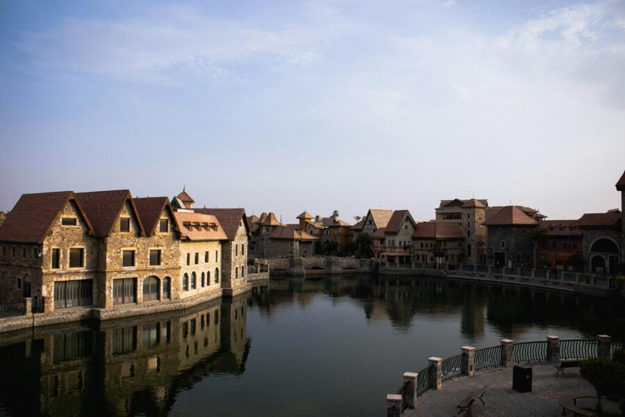 Traditional stone buildings reflect on a calm canal in Dubai, capturing architectural charm.