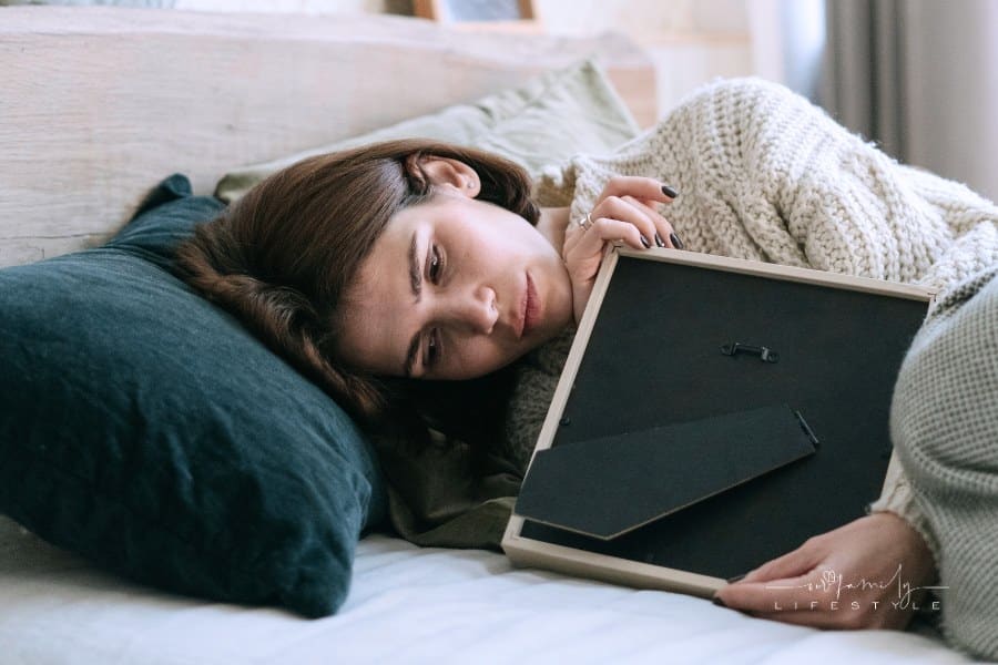 A Woman Lying on the Bed while Holding a Picture Frame