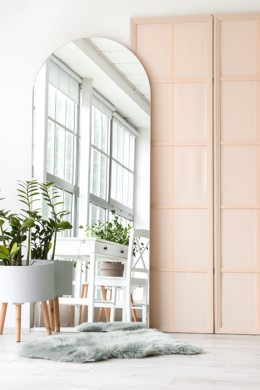 modern living room wihth peach accent wall and large mirror reflecting floor-to-ceiling windows