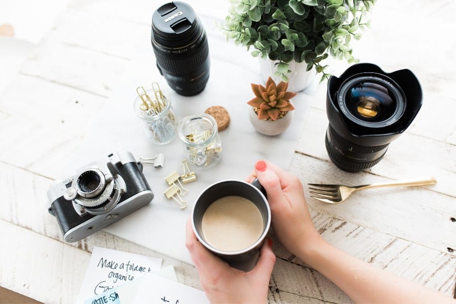 Hand Holding Coffee with Photography Equipment on white desktop