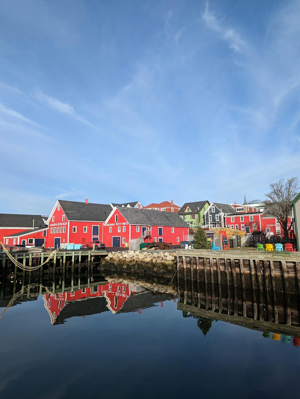 Vibrant red buildings reflected on calm waters in Lunenburg, Nova Scotia.