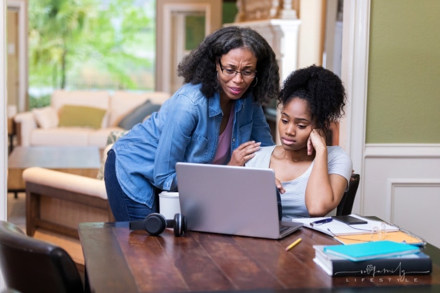mom comforts college age daughter looking at laptop
