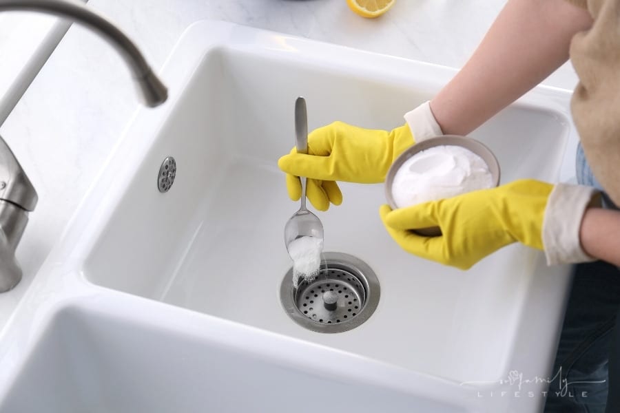 woman using baking soda to unclog a sink