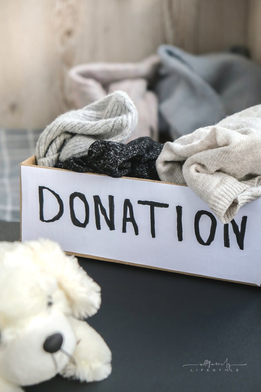 donation box filled with gently used kids' clothes and stuffed dog nearby