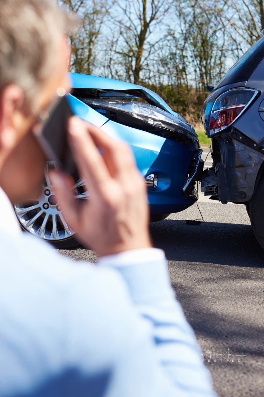 man talking on phone while looking at car accident in front of him