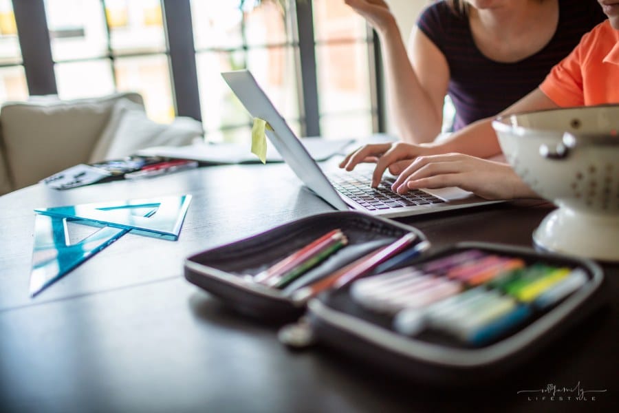 Mother homeschooling teenage boy from home on a dinner table