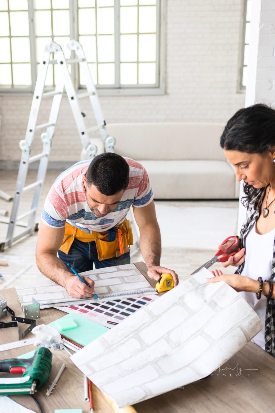 Couple cutting brinck wallpaper for home improvement project