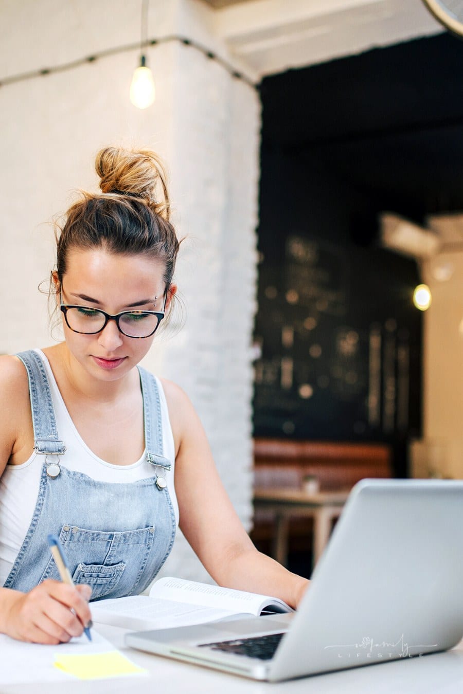 young woman taking notes during online learning class