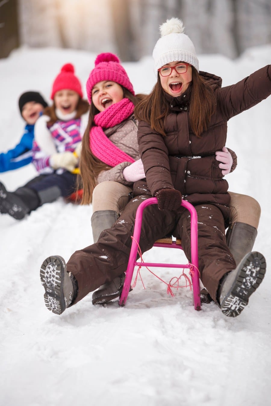 group of kids sledding down a snowhill