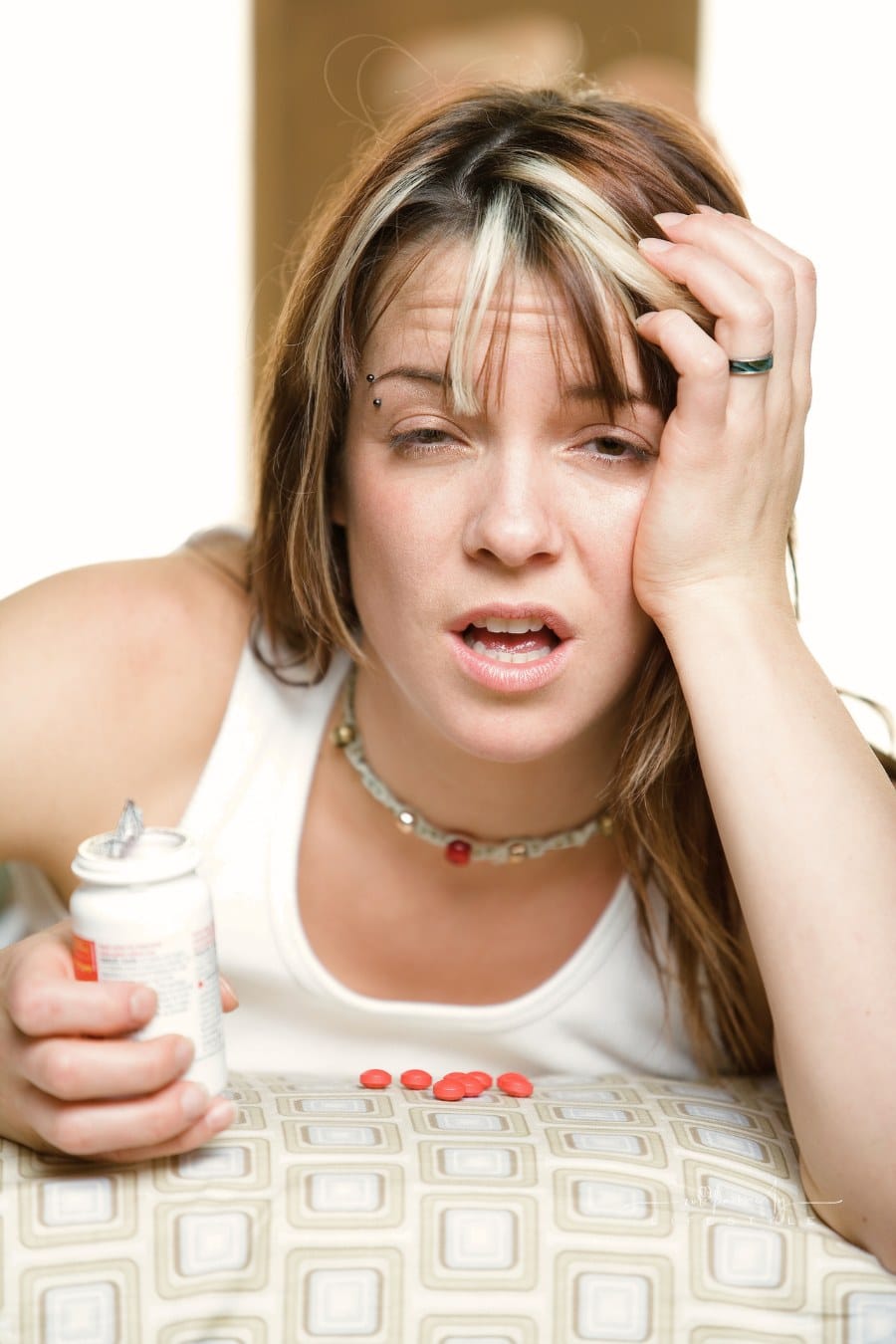 Woman with hangover taking pills