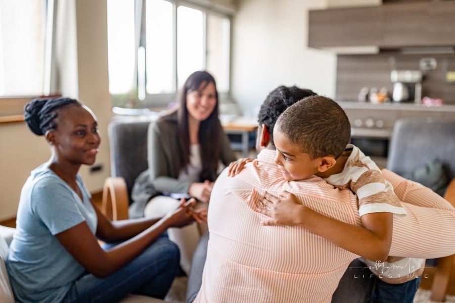 Family in a parenting coach therapy session with young son hugging dad