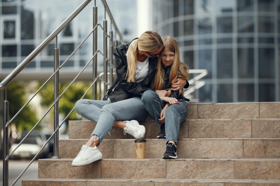 Woman embracing child on city stairs, conveying warmth and connection.