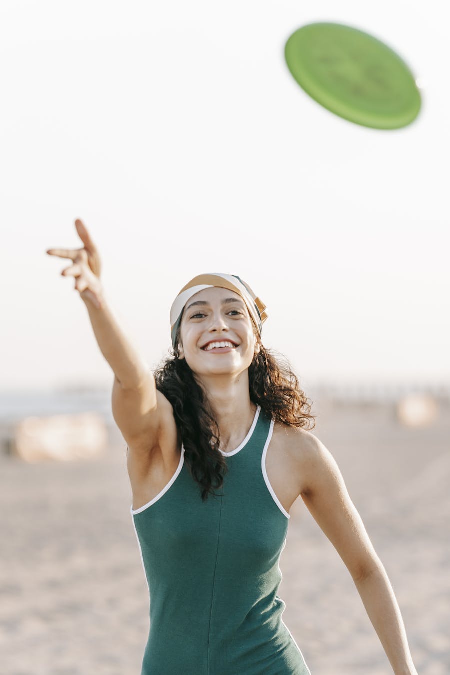 Woman enjoying a day at the beach, playing frisbee and smiling under the sun.