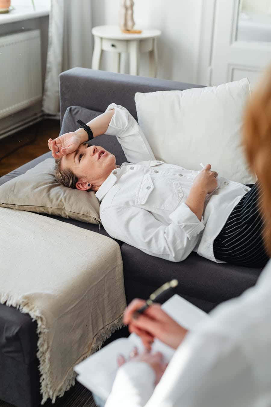 Woman lying on couch during therapy session, expressing concern.
