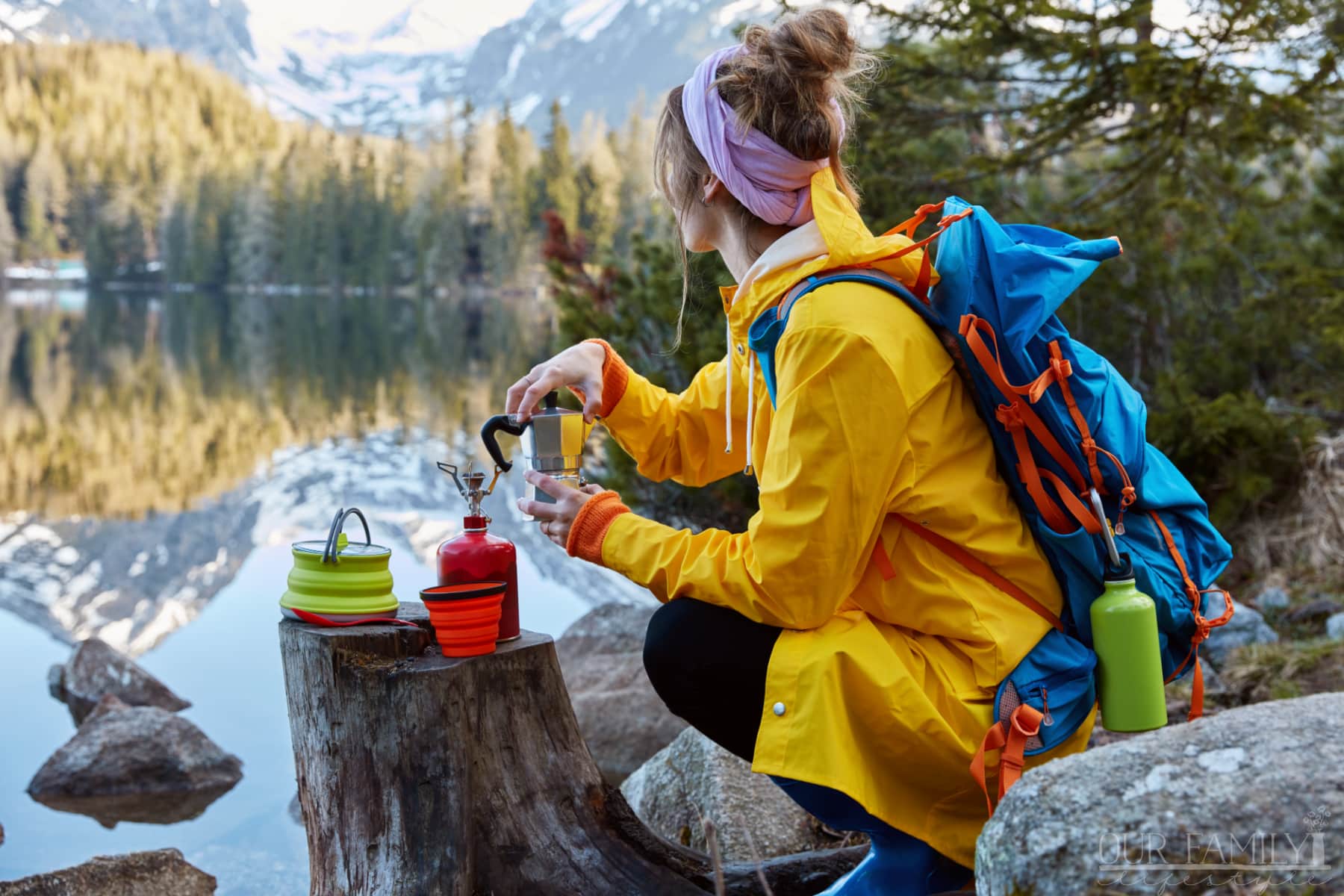 woman overlooking mountain lake with camping gear in hand