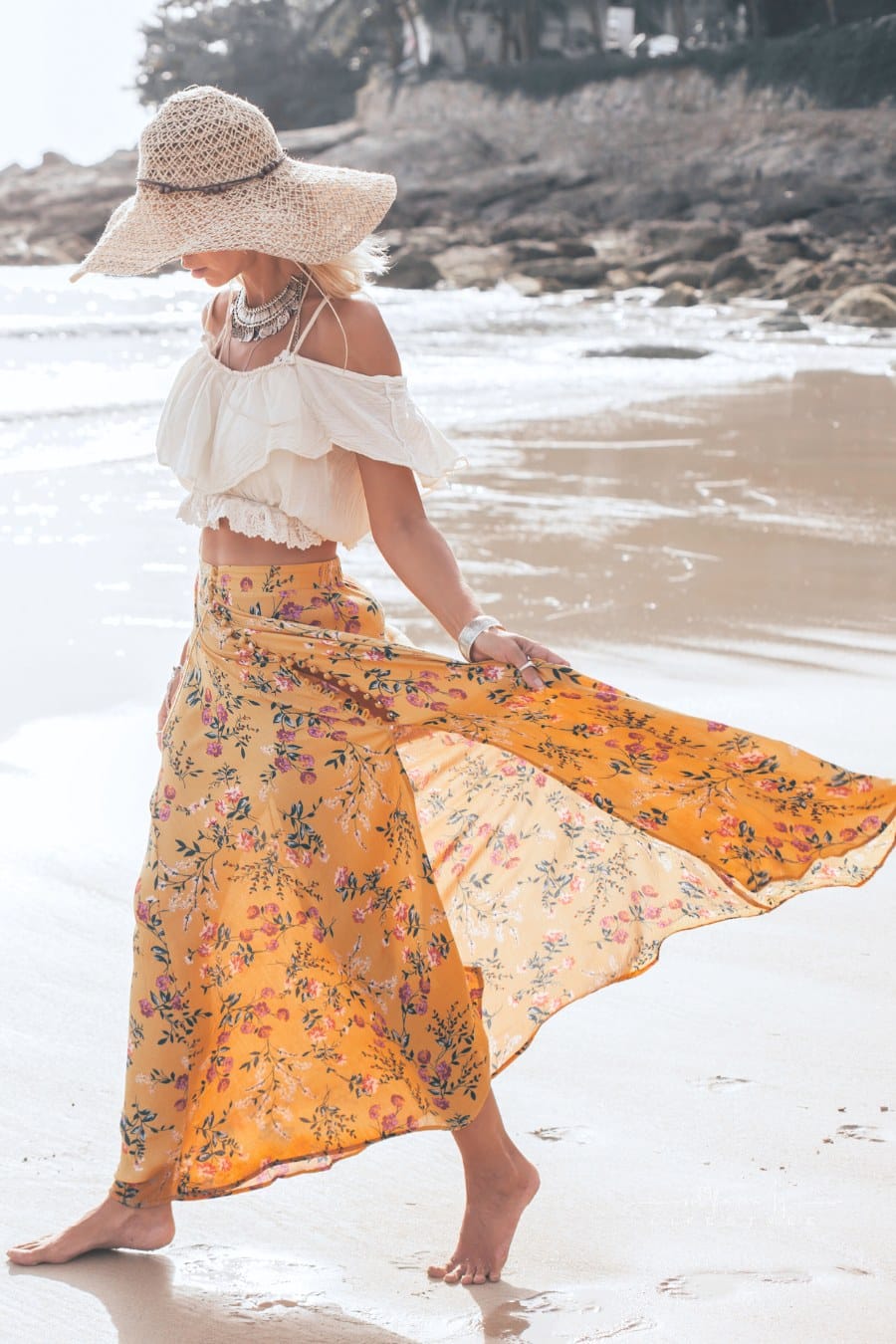 woman wearing flowing, floral maxi skirt and sun hat while walking a beach in Phuket, Thailand