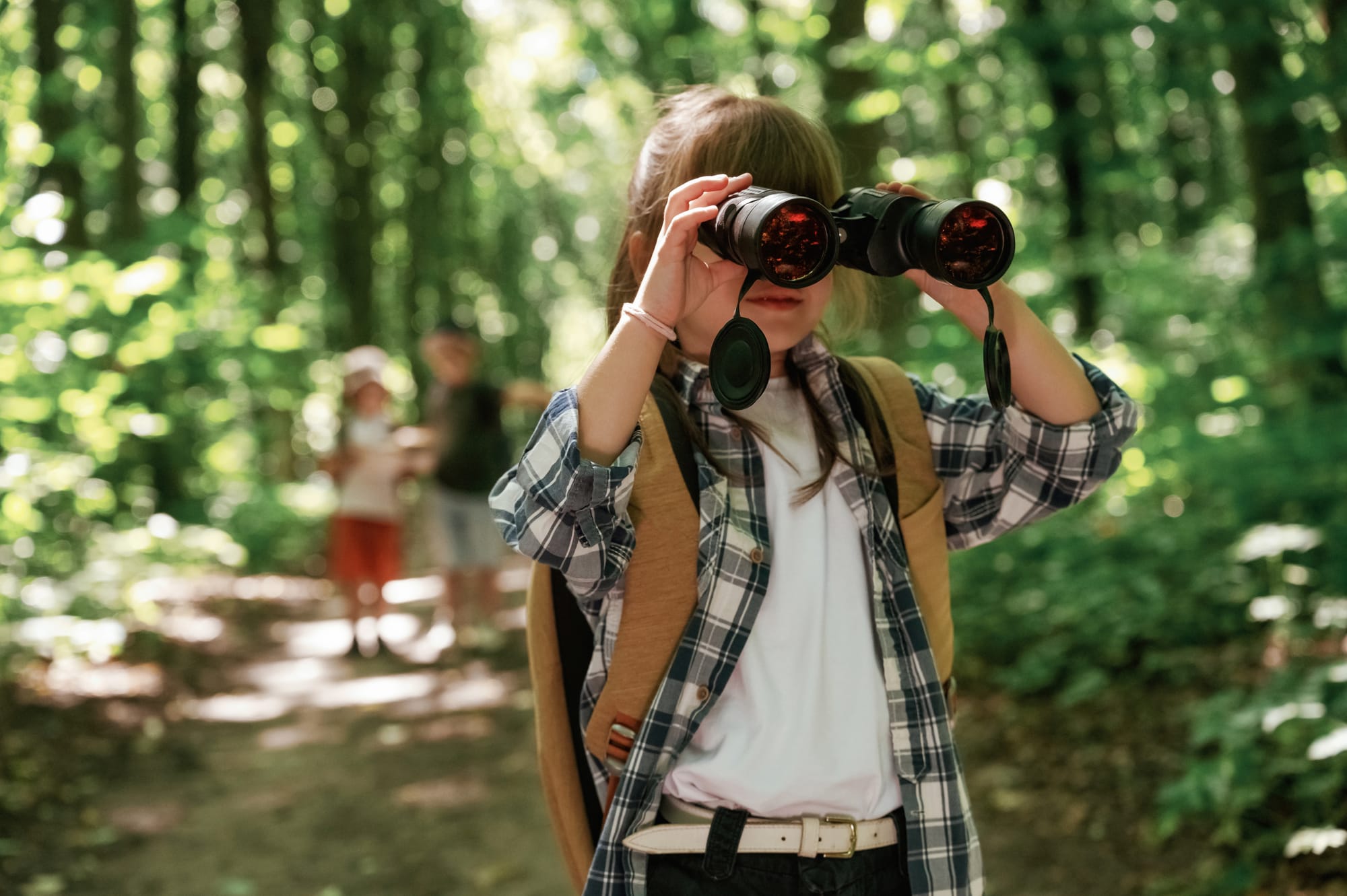 Binoculars in hands kids in forest at summer daytime together