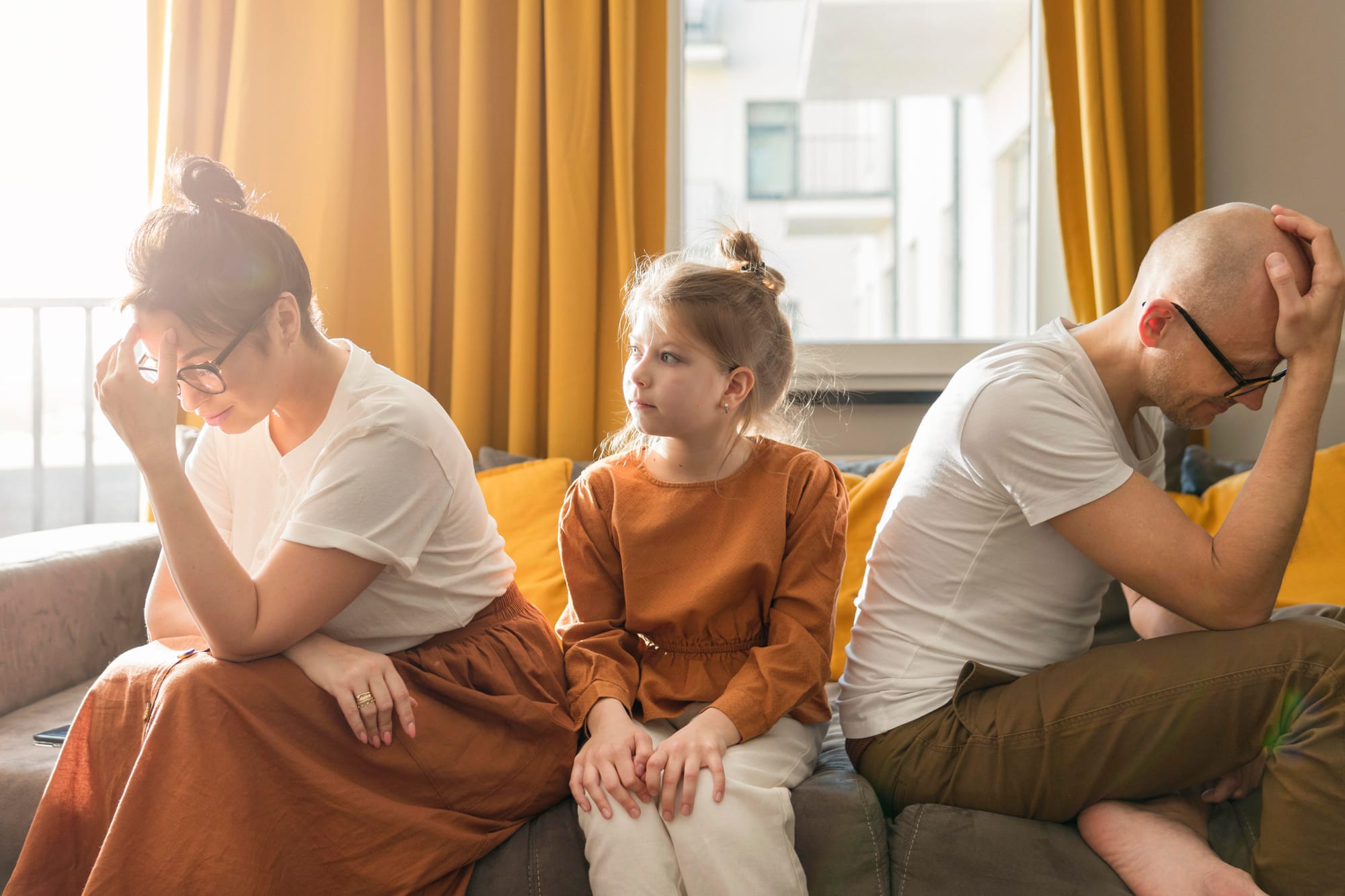 divorcing couple upset with young daughter sitting between them