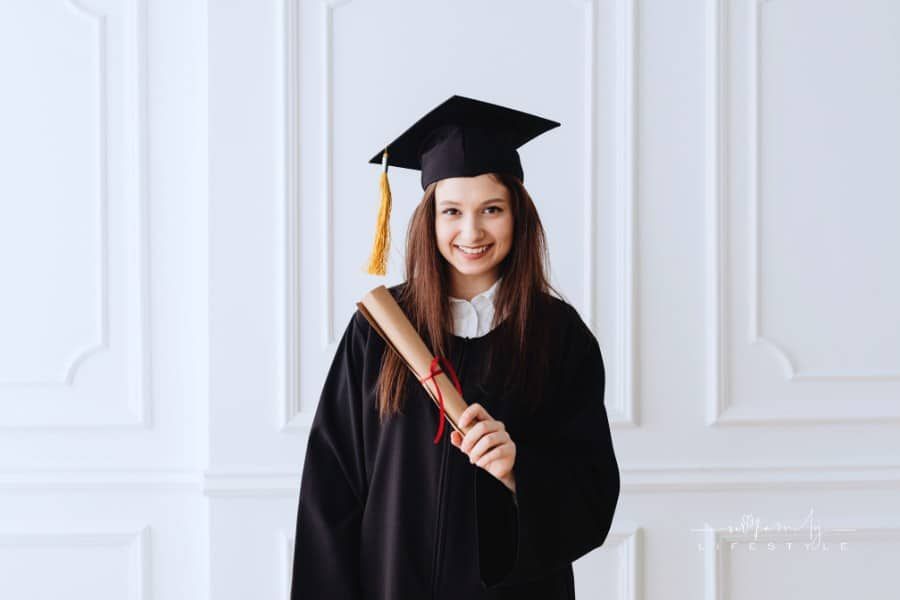 female graduate in cap and gown holding a scroll diploma