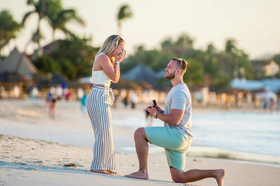 A couple shares a loving moment during a beach proposal in Antigua at sunset.