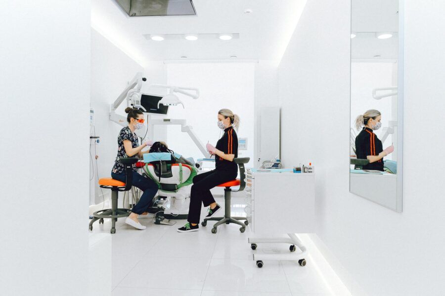 A dental clinic scene featuring professionals in masks attending to a patient with modern equipment.
