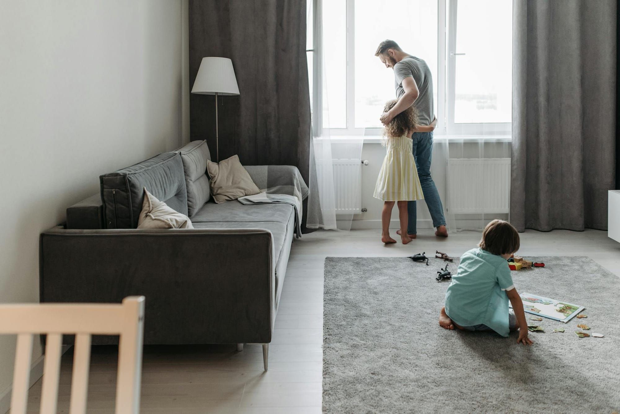 A father bonding with his children in a bright, modern living room setting.