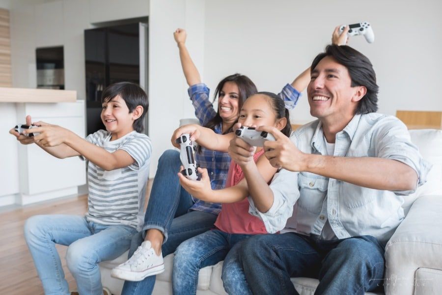 family sitting on couch having fun playing video games together