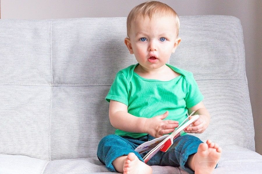 baby holding a board book and looking directly at the camera