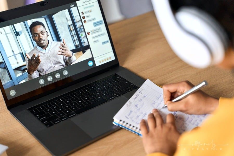 female college student taking notes with online tutor on laptop